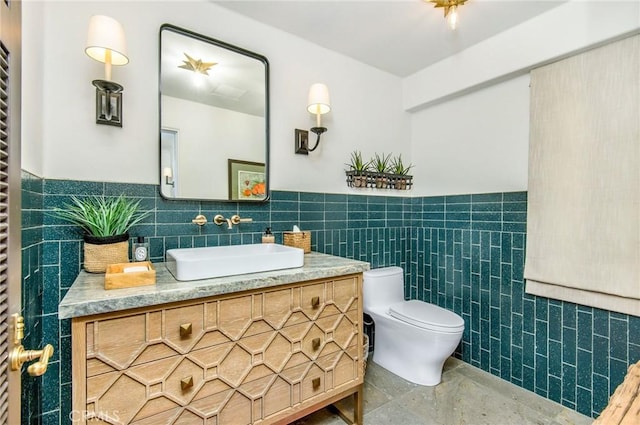 bathroom featuring vanity, tile walls, and toilet