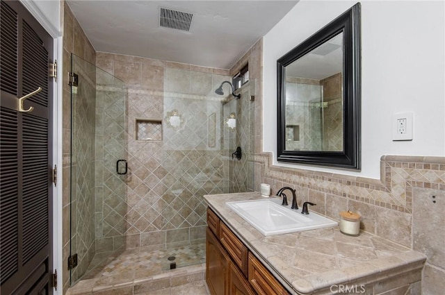 bathroom featuring vanity, tile walls, and walk in shower