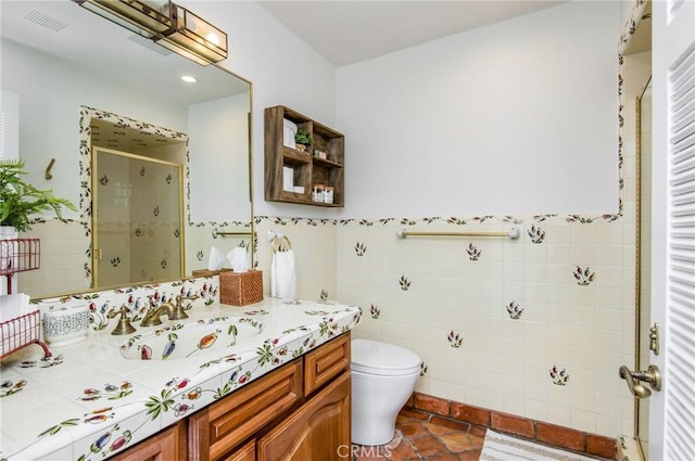 bathroom with tile patterned floors, an enclosed shower, vanity, tile walls, and toilet