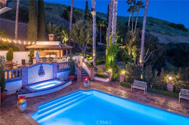 view of swimming pool with an in ground hot tub, a mountain view, a patio, and area for grilling