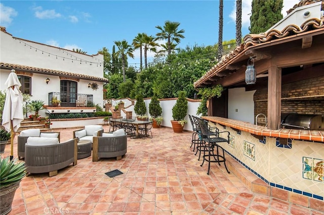 view of patio / terrace with area for grilling, an outdoor living space, and a bar