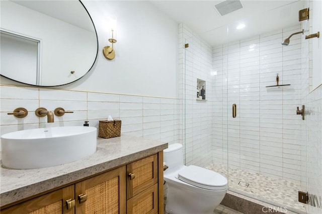 bathroom with vanity, toilet, an enclosed shower, and tile walls