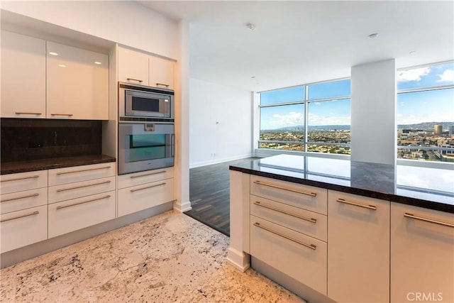 kitchen featuring dark stone countertops, dark hardwood / wood-style flooring, white cabinets, and appliances with stainless steel finishes