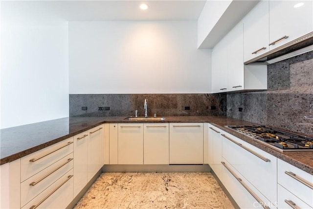 kitchen with kitchen peninsula, decorative backsplash, sink, dark stone countertops, and stainless steel gas stovetop