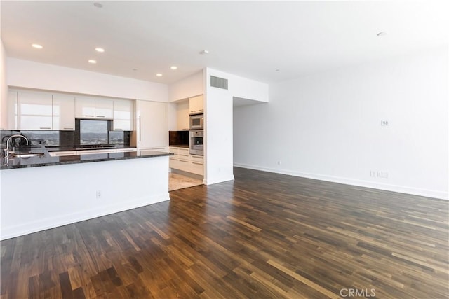 kitchen with decorative backsplash, appliances with stainless steel finishes, sink, white cabinets, and dark hardwood / wood-style floors