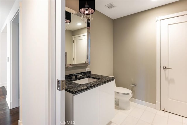 bathroom featuring toilet, vanity, hardwood / wood-style flooring, and an inviting chandelier