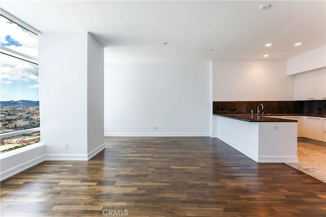 kitchen featuring white cabinets, tasteful backsplash, dark wood-type flooring, and sink