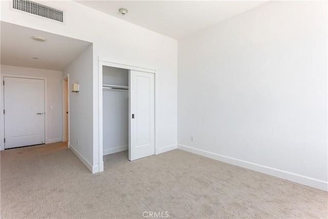 unfurnished bedroom featuring light colored carpet and a closet