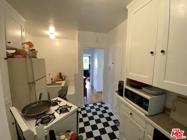 kitchen with white appliances, white cabinets, and light tile floors