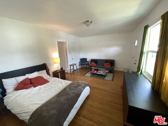 bedroom with dark hardwood / wood-style floors and multiple windows