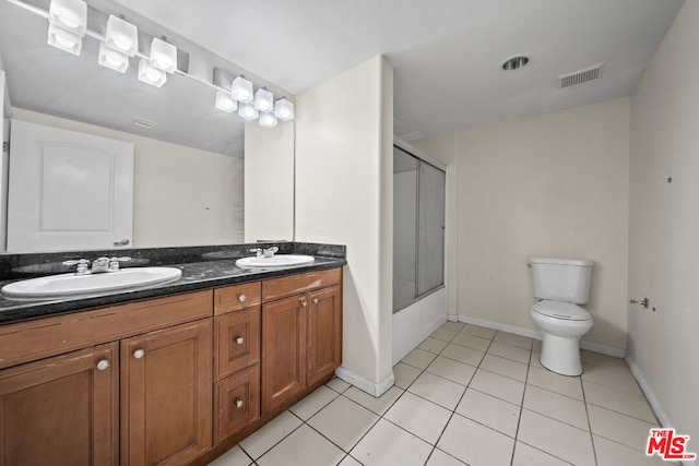 bathroom with tile flooring, double sink, toilet, and large vanity