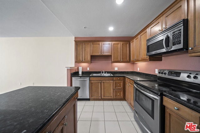 kitchen featuring dark stone counters, sink, light tile floors, and appliances with stainless steel finishes