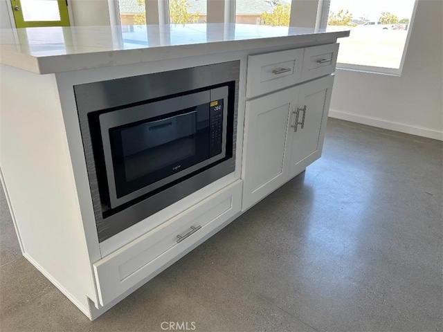 room details with stainless steel microwave, white cabinets, and a kitchen island