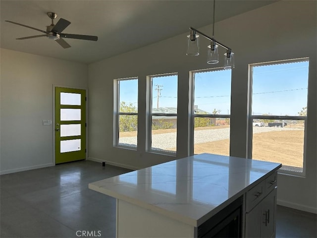 kitchen featuring decorative light fixtures, ceiling fan, beverage cooler, and light stone counters