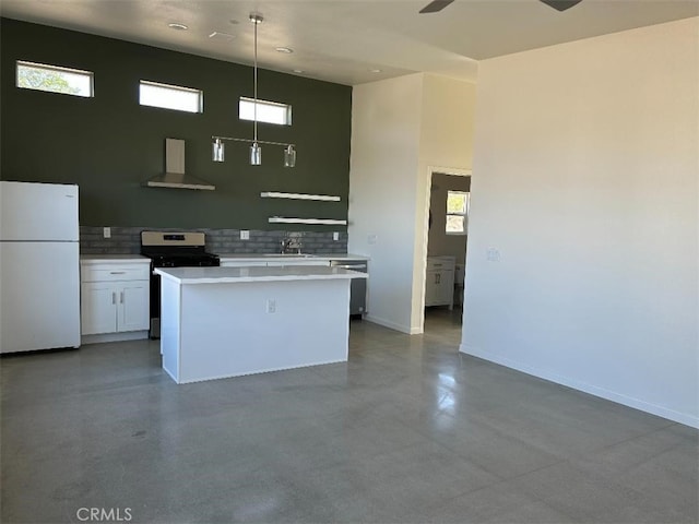 kitchen featuring decorative light fixtures, wall chimney range hood, white cabinetry, white refrigerator, and gas range