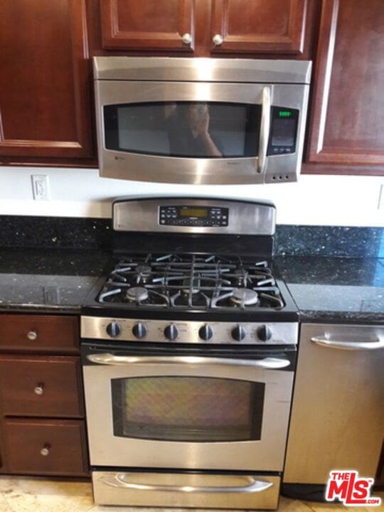 kitchen with dark stone counters and stainless steel appliances