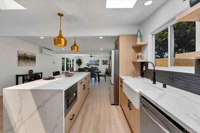 kitchen featuring a skylight, stainless steel appliances, hanging light fixtures, light stone countertops, and light wood-type flooring