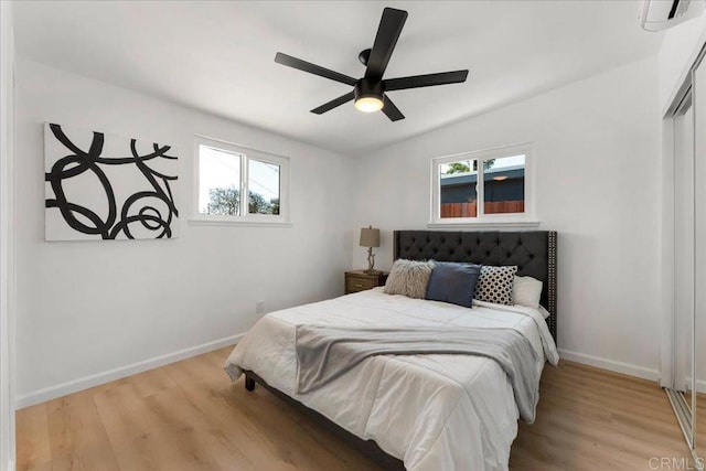 bedroom featuring ceiling fan, multiple windows, light hardwood / wood-style floors, and a closet