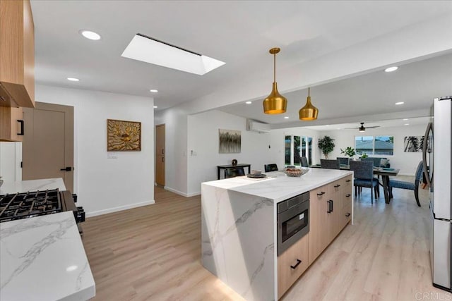 kitchen with decorative light fixtures, light wood-type flooring, a skylight, and ceiling fan