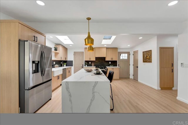 kitchen featuring a kitchen island, light wood-type flooring, stainless steel fridge with ice dispenser, and backsplash