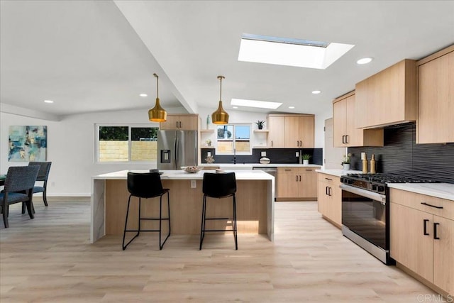 kitchen with light hardwood / wood-style flooring, a kitchen island, hanging light fixtures, tasteful backsplash, and appliances with stainless steel finishes