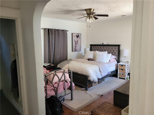 bedroom featuring a textured ceiling, ceiling fan, and wood-type flooring