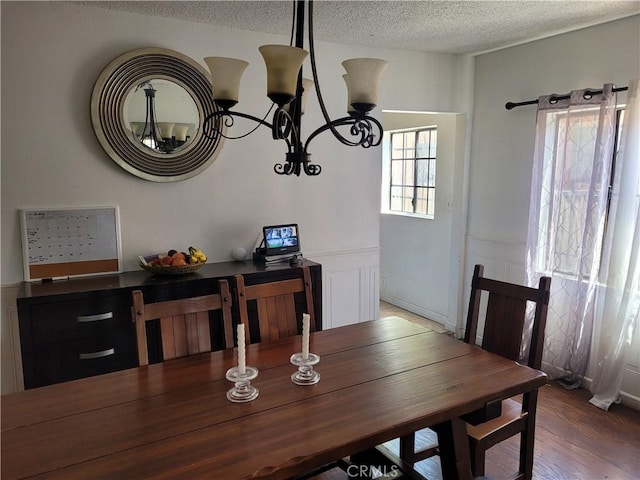 dining area featuring a textured ceiling, hardwood / wood-style floors, and a notable chandelier