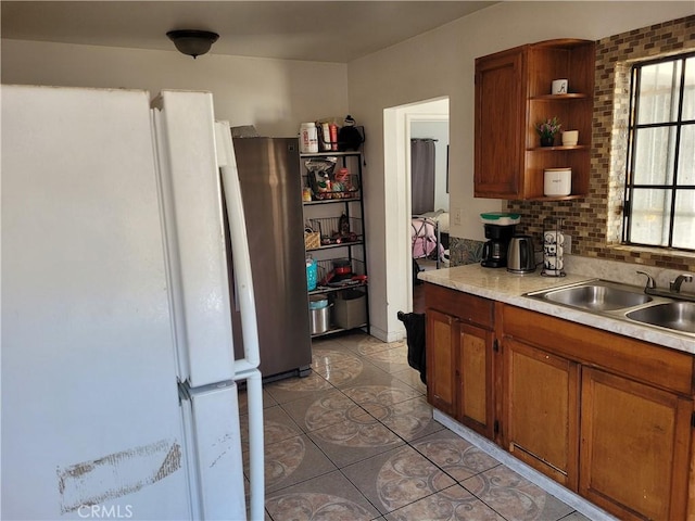 kitchen featuring white fridge, stainless steel fridge, backsplash, light tile patterned flooring, and sink