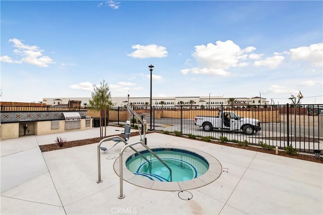 view of pool with a community hot tub, exterior kitchen, and a patio