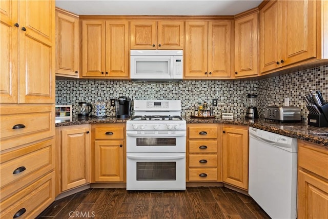 kitchen featuring backsplash, dark stone countertops, and white appliances