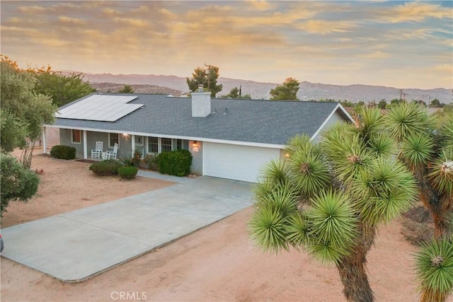 view of front of property featuring a mountain view, a garage, solar panels, and a porch