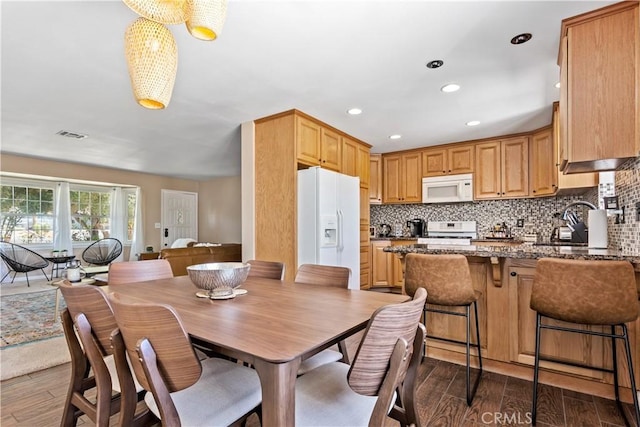 kitchen featuring white appliances, dark hardwood / wood-style flooring, dark stone counters, and tasteful backsplash