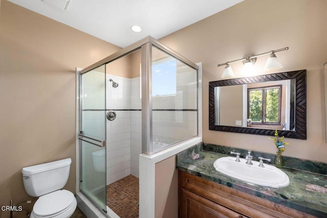 bathroom featuring a shower with door, vanity, and toilet