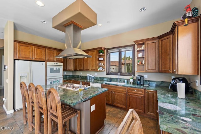 kitchen with white appliances, sink, dark stone countertops, a kitchen island, and a kitchen bar