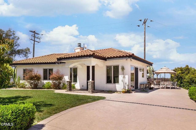 back of property with a lawn and a patio area