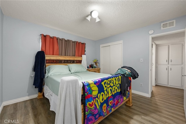 bedroom with dark wood-style floors, a closet, visible vents, and baseboards