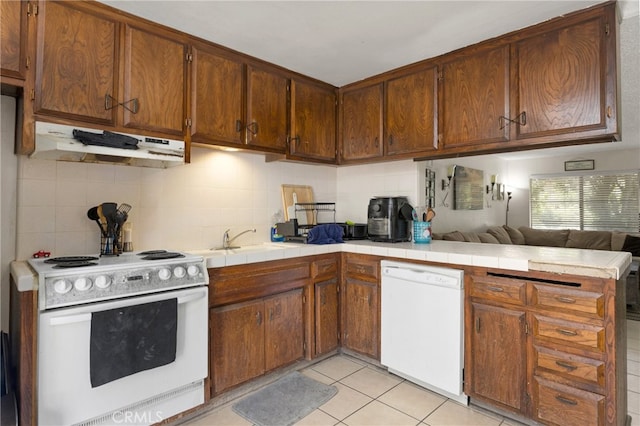 kitchen featuring tile countertops, light tile patterned flooring, white appliances, and sink