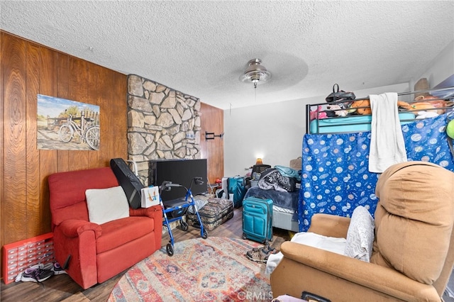 living room with hardwood / wood-style floors, ceiling fan, wood walls, and a textured ceiling