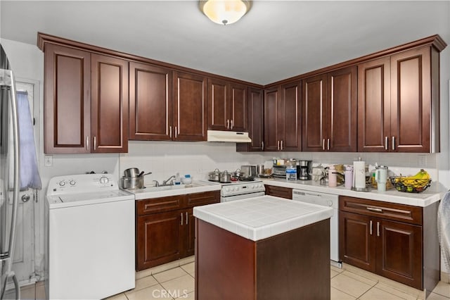 kitchen featuring a center island, light tile patterned flooring, white appliances, and washer / dryer