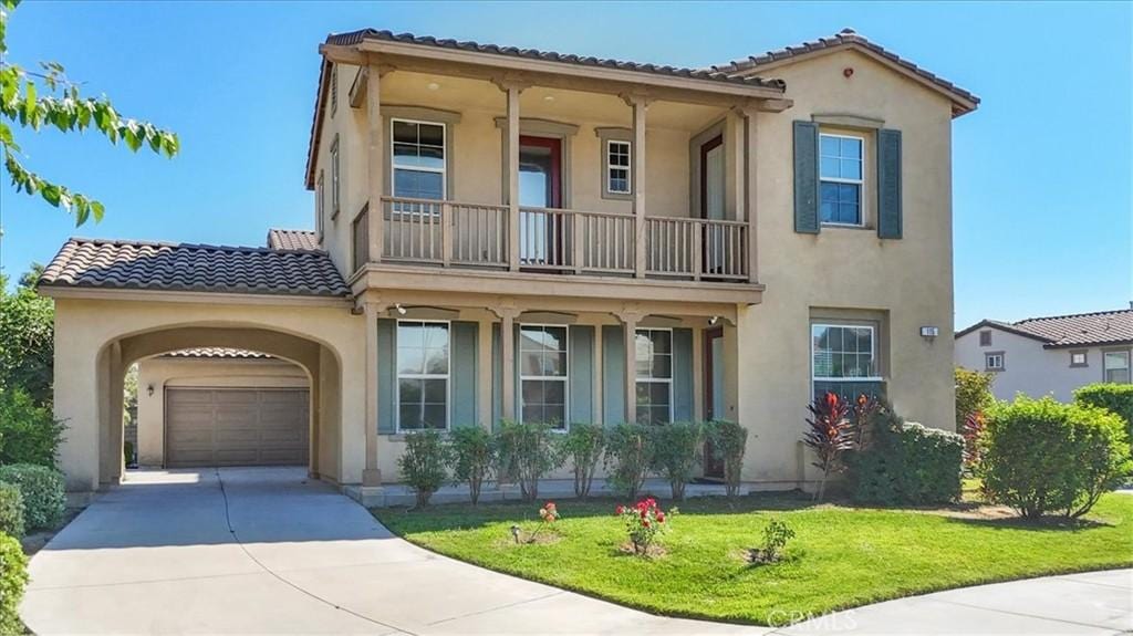 mediterranean / spanish home with a garage, a balcony, and a front lawn