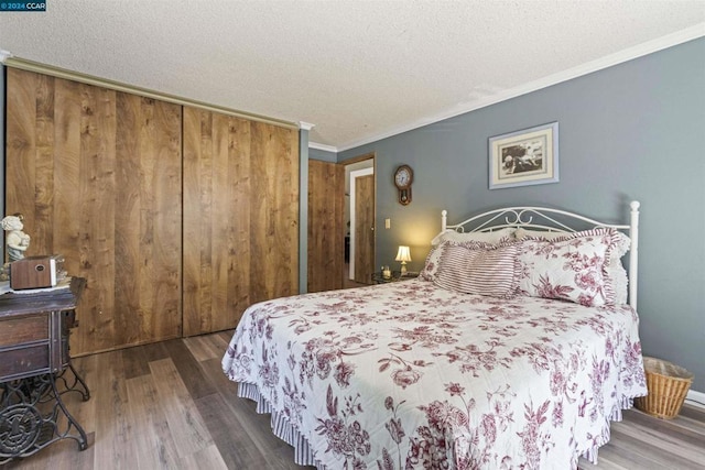 bedroom with ornamental molding, hardwood / wood-style floors, a textured ceiling, and a closet