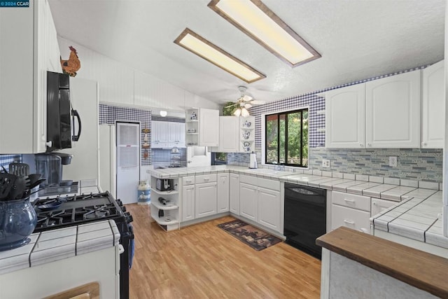 kitchen featuring dishwasher, tile counters, white cabinets, and gas range