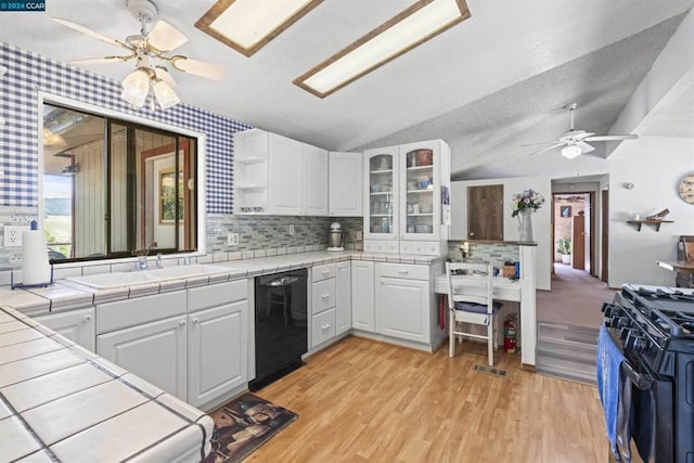 kitchen featuring lofted ceiling, white cabinets, tile countertops, and dishwasher