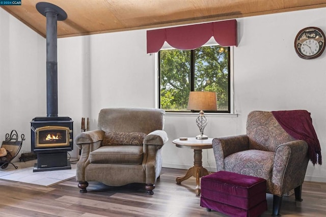 sitting room with wood-type flooring, a wood stove, and wood ceiling