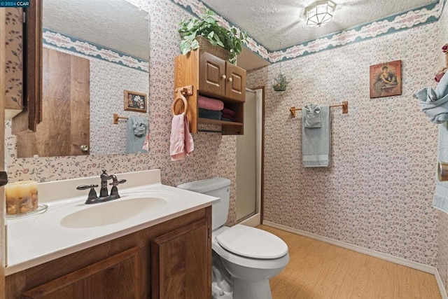 bathroom with toilet, a shower with shower door, wood-type flooring, a textured ceiling, and vanity