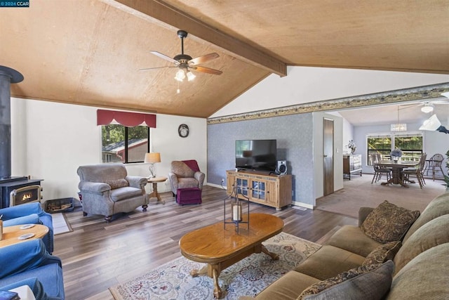 living room with a healthy amount of sunlight, dark hardwood / wood-style flooring, lofted ceiling with beams, and a wood stove