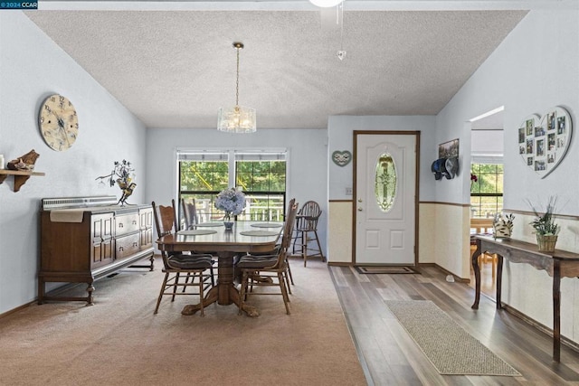 dining area with lofted ceiling, a notable chandelier, wood-type flooring, and a healthy amount of sunlight