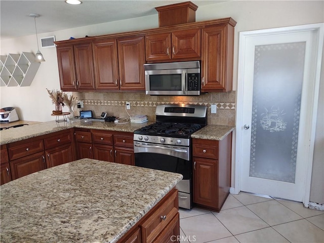 kitchen with light stone countertops, stainless steel appliances, decorative backsplash, and pendant lighting