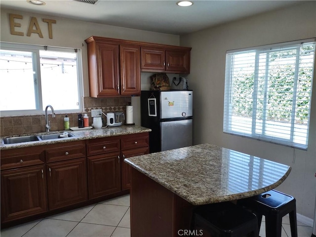 kitchen featuring stainless steel refrigerator, plenty of natural light, sink, and tasteful backsplash