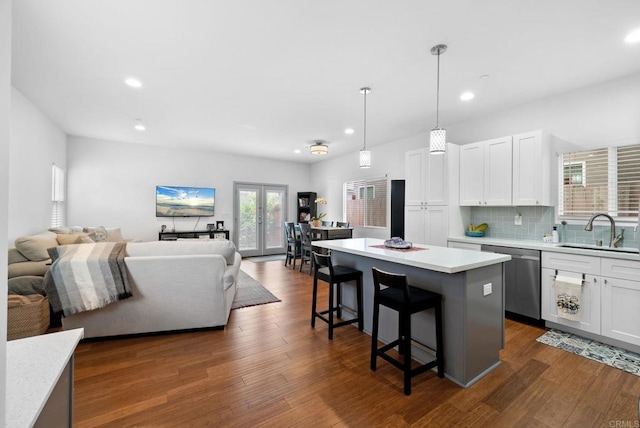 kitchen featuring stainless steel dishwasher, sink, dark hardwood / wood-style flooring, and white cabinets